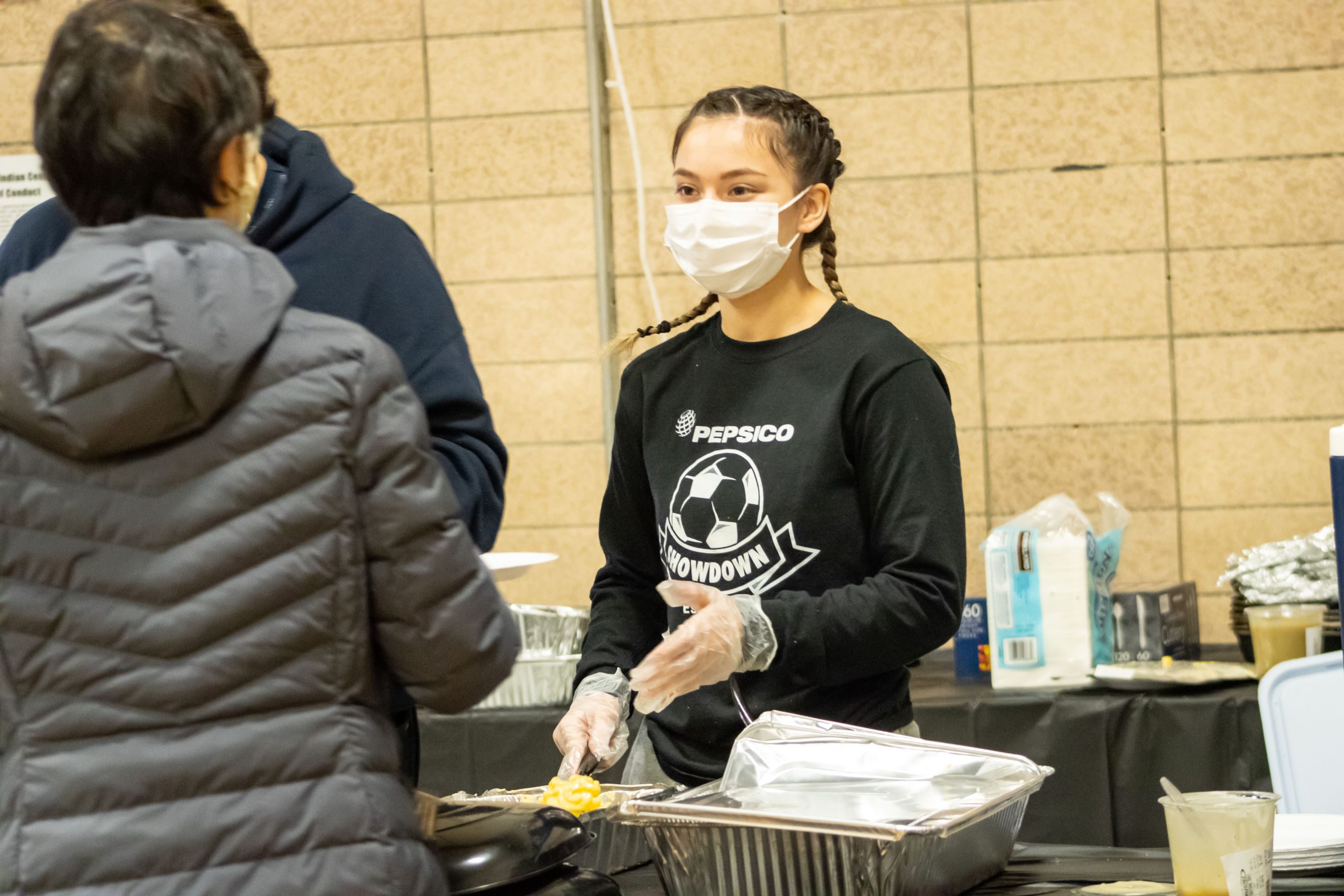 Photo shows Angelina Serna, Pritzker College Prep student, serving meals at the American Indian Center