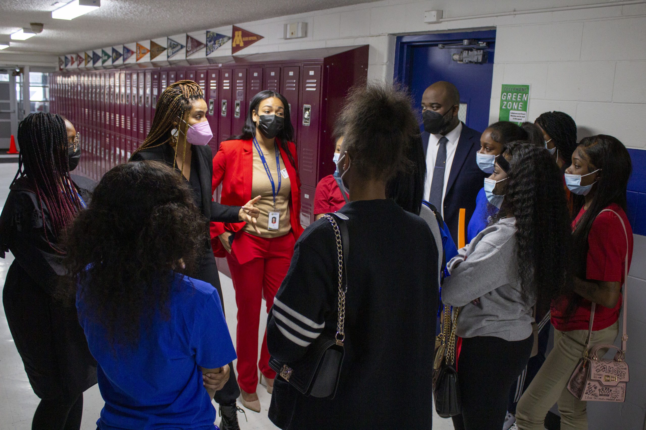 Image shows students in the hallways of Johnson College Prep, talking with Noble Schools' CEO Constance Jones, JCP principal Jonas Cleaves and other Noble staff after the Hope Chicago announcement that they would be able to go to college for free
