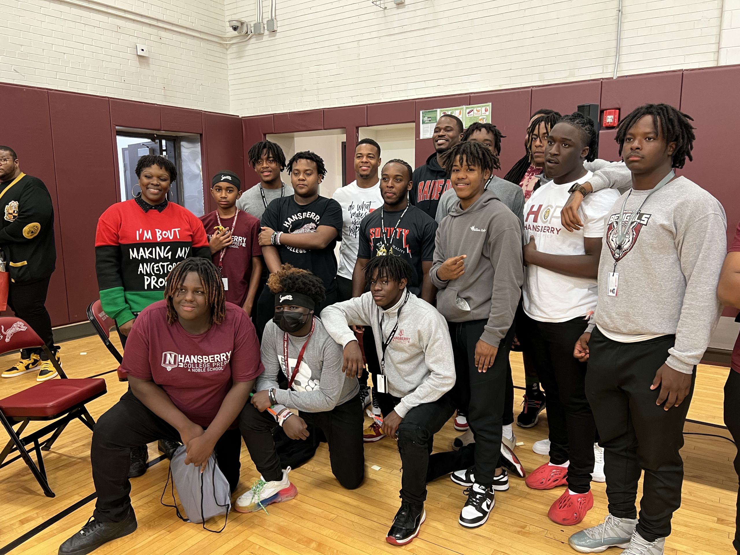 Photo shows Black male students at Hansberry College Prep and Kameshia Ward, posing for a photo with Chicago Bulls player Javonte Green and former NFL player Pierre Thomas at Hansberry's Black Boy Joy social.