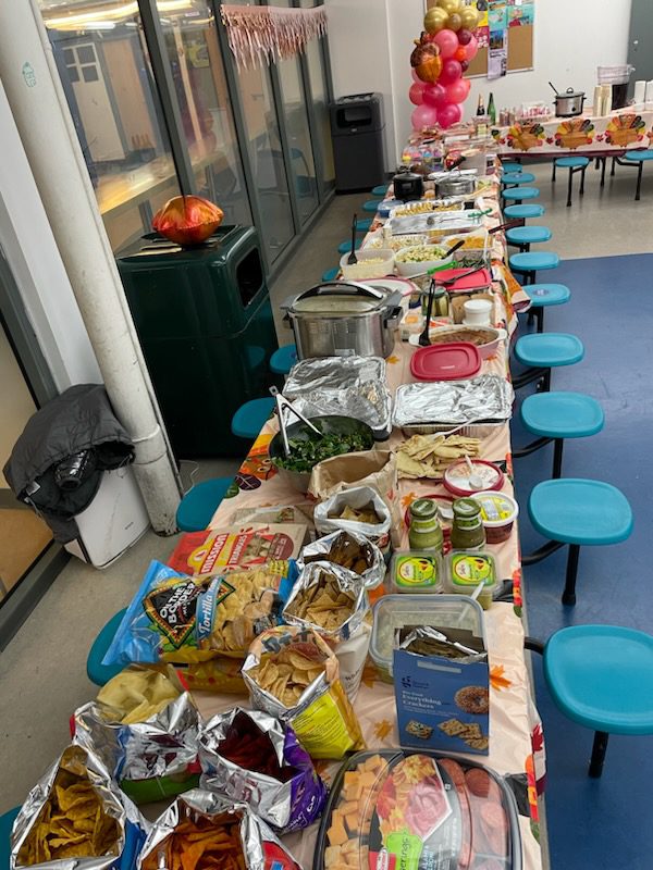 Image shows a cafeteria table at Muchin College Prep laden with all sorts of foods for the staff-only Thanksgiving meal