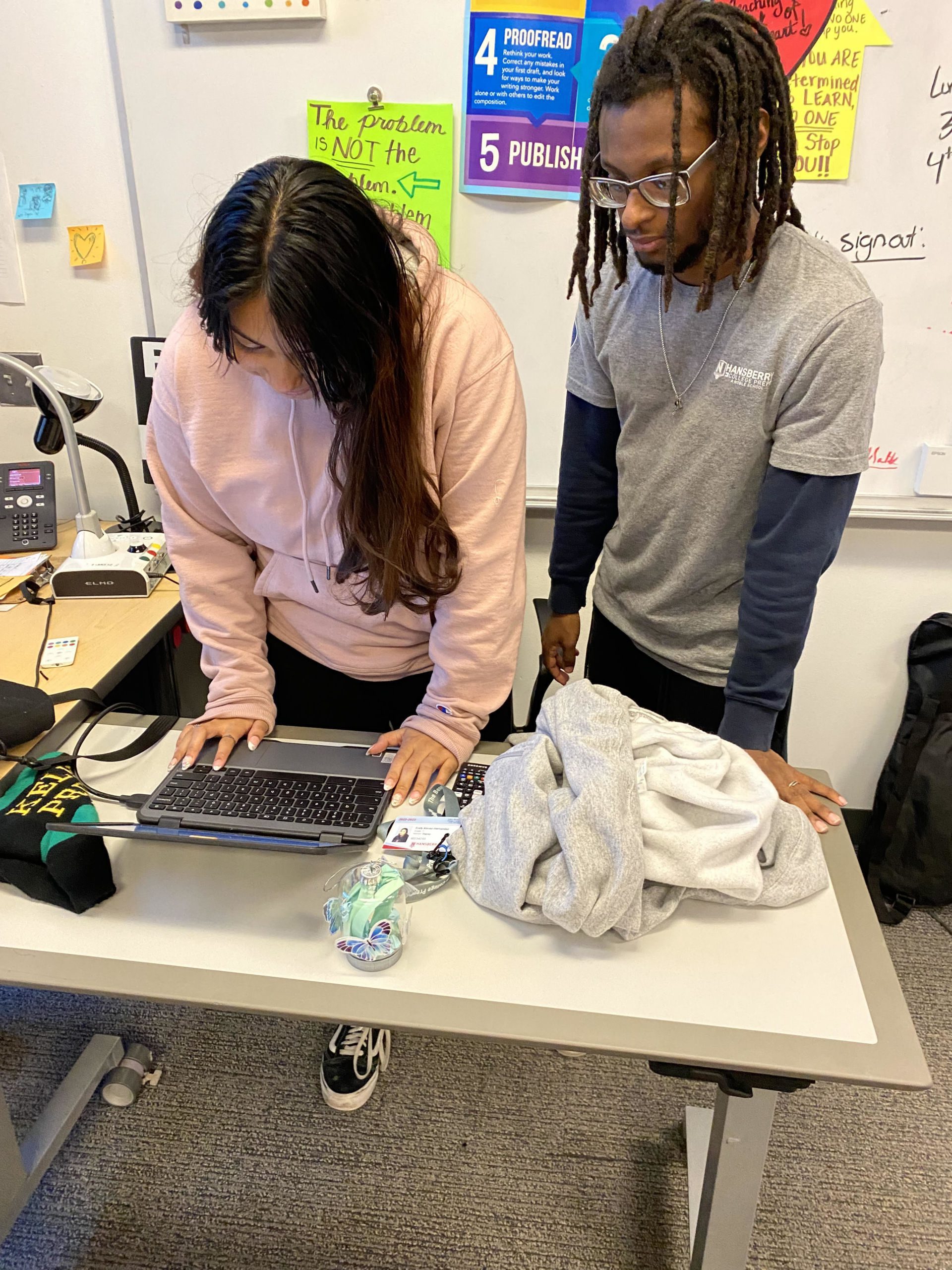 Photo shows two Hansberry College Prep students, Evely and Brendan, stooping over a classroom desk and looking at a laptop. Both students are a part of the Beats Club at Hansberry.