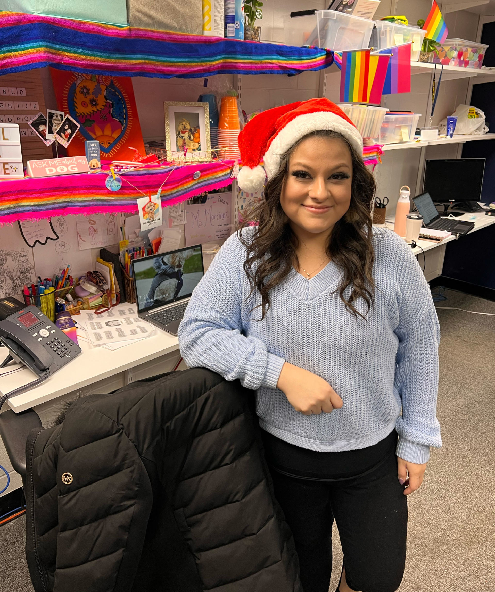 Photo shows Noble Street College Prep social worker Cynthia Martinez wearing a Santa hat in her office, decked out with holiday decorations.