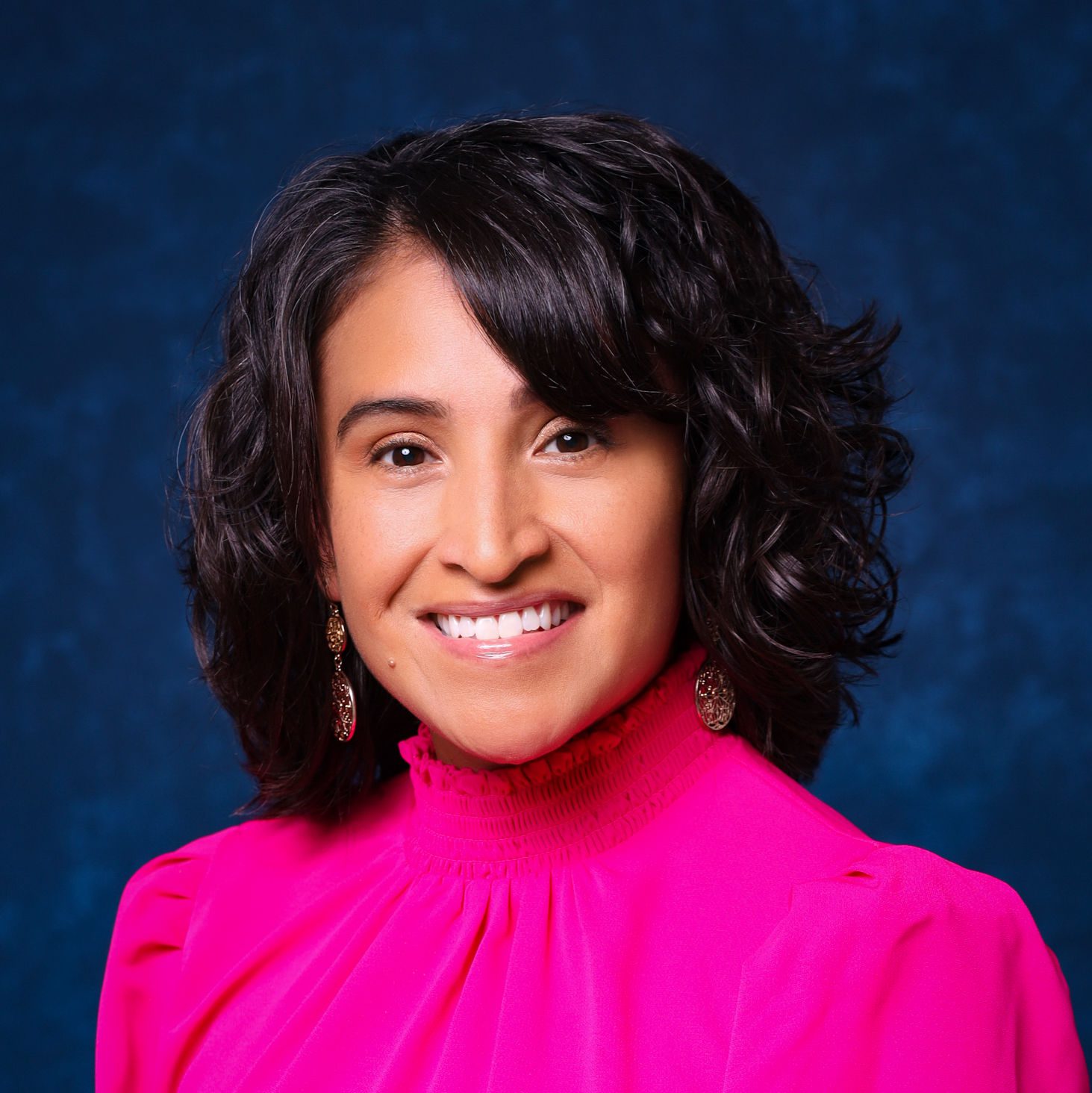Photo shows a headshot of Norma Gutierrez in a bright pink blouse with a high collar. Gutierrez works as the Assistant Director of Student Experience at Noble Schools, a charter school network in Chicago, IL.