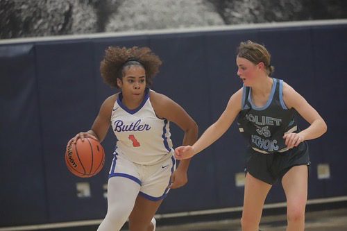 In this photo, Xamiya, one of the team captains of the Butler College Prep varsity girls basketball team, dribbles around an opposing player at the regional championship game. Photo by Chris Samelton.