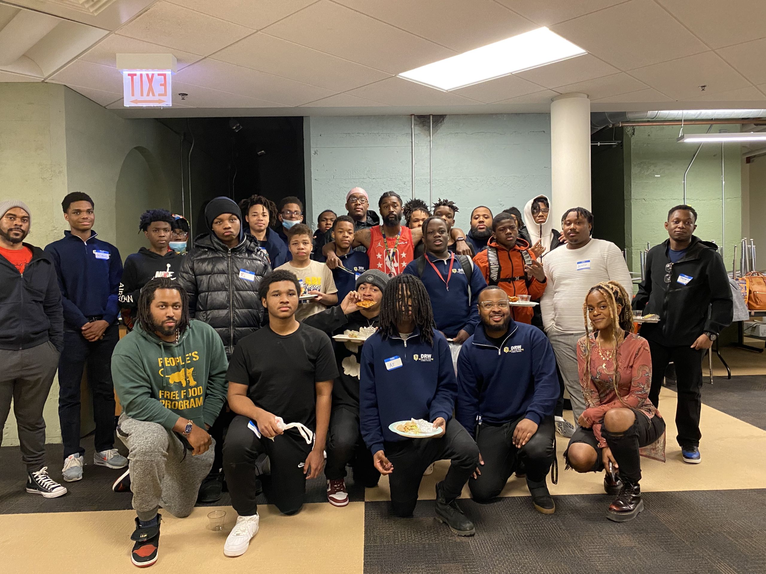 Photo shows a group of Black boys at DRW College Prep, posing with staff and guests from The CornerStore Chicago after their Black Boys Heal: See Me, Hear Me event.