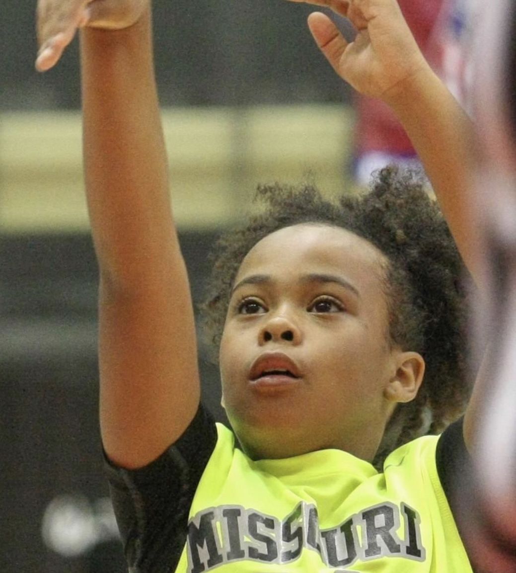 Photo shows a young Xamiya shooting a basketball. She is wearing a bright neon green jersey that says "Missouri Elite" with the number 24 on it.