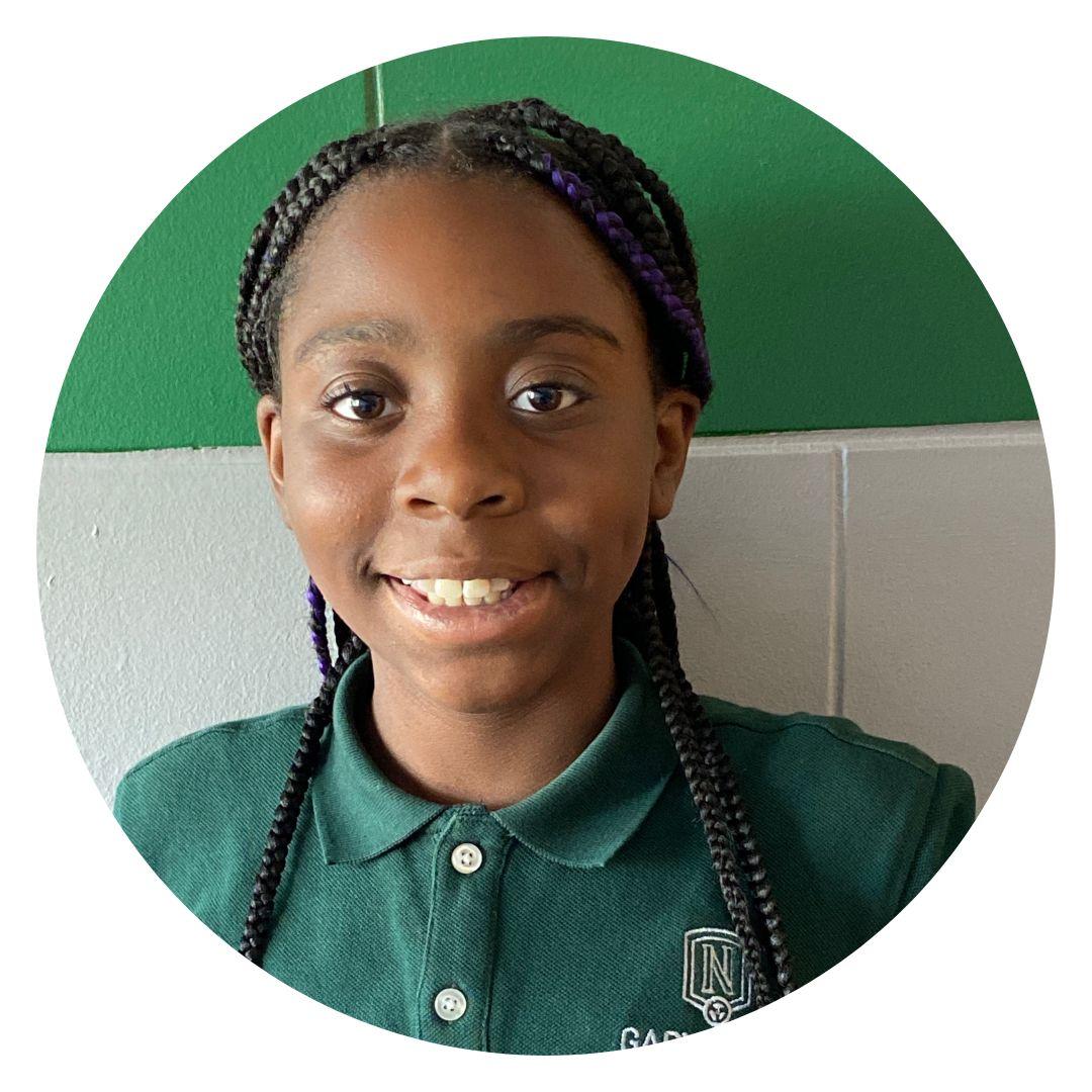 This photo shows a headshot of Trinity Bridge, a 6th grader at Gary Comer Middle School in Chicago, IL. Trinity is a young Black girl with dark brown braids and she is wearing a dark green polo with the Gary Comer Middle School logo on it.