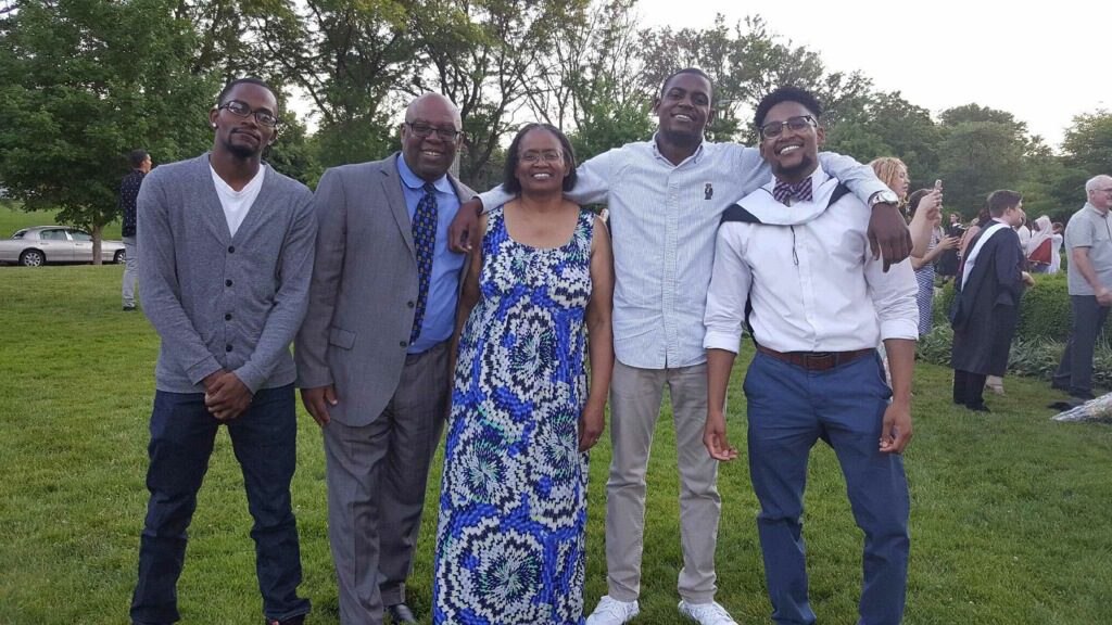 Emmanuel Jackson with his family celebrating his graduation of University of Chicago. Jackson is on the right wearing a white dress shirt with his graduation sash over his shoulder.