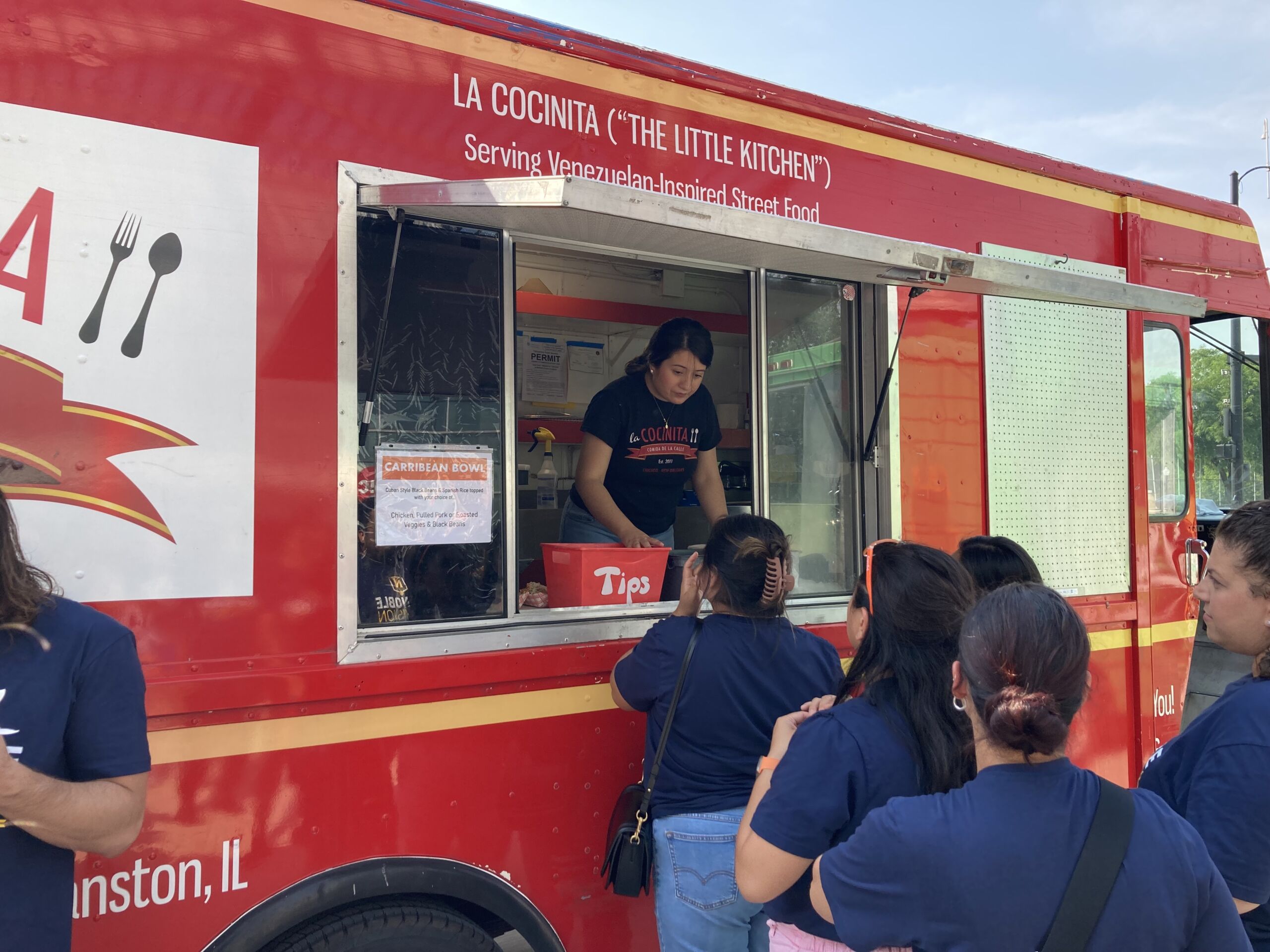 Photo shows a close-up of a Noble Schools' staff member ordering at the red La Concinita food truck. You can see other staff lined up behind her.