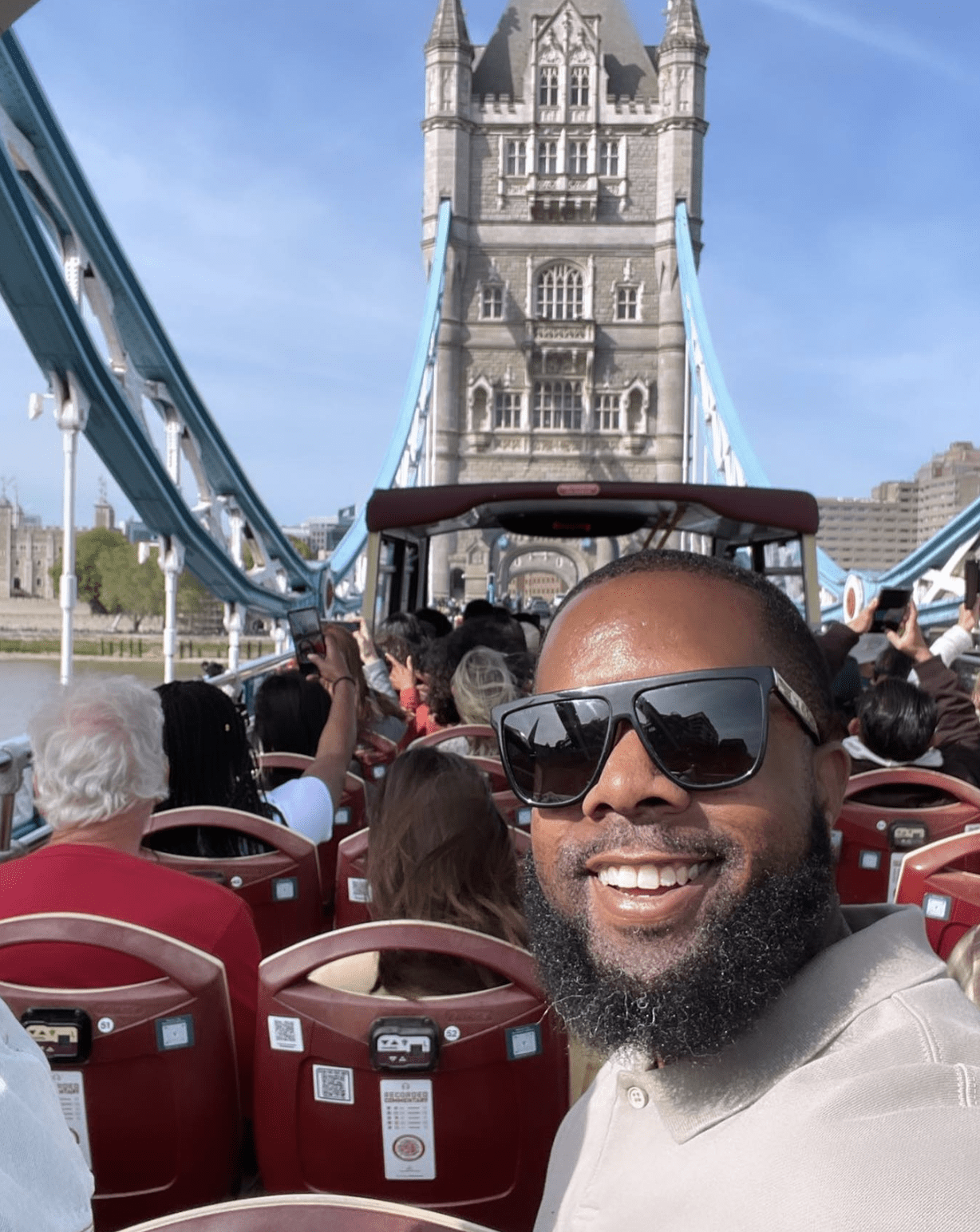 Photo shows a selfie of Principal Brian Riddick on one of his travel trips. He is on a tour bus in front of a historical building.