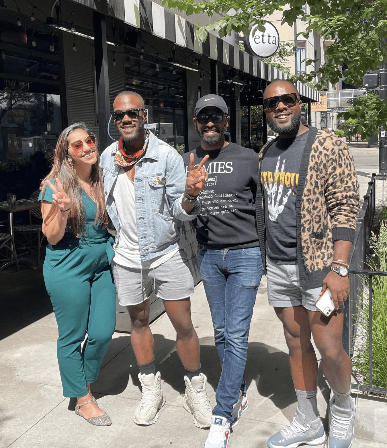 Photo shows Principal Brian Riddick in casual summer clothing with three friends. They are outside of a restaurant in Chicago on a sunny day.