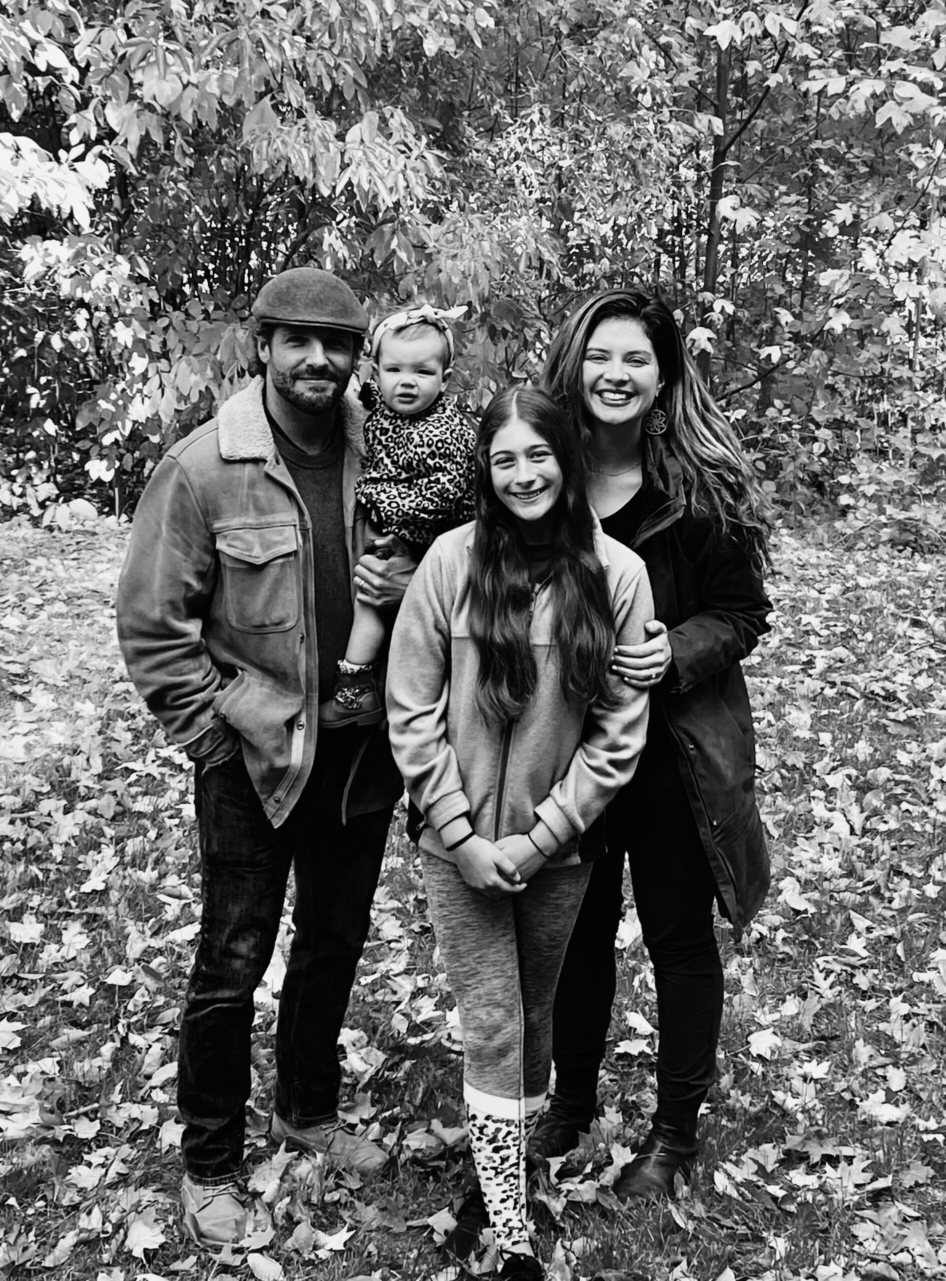 A black and white photo of Principal Jessie Weingartner and her family. They are outside with lots of leaves on the ground and are wearing fall clothes.