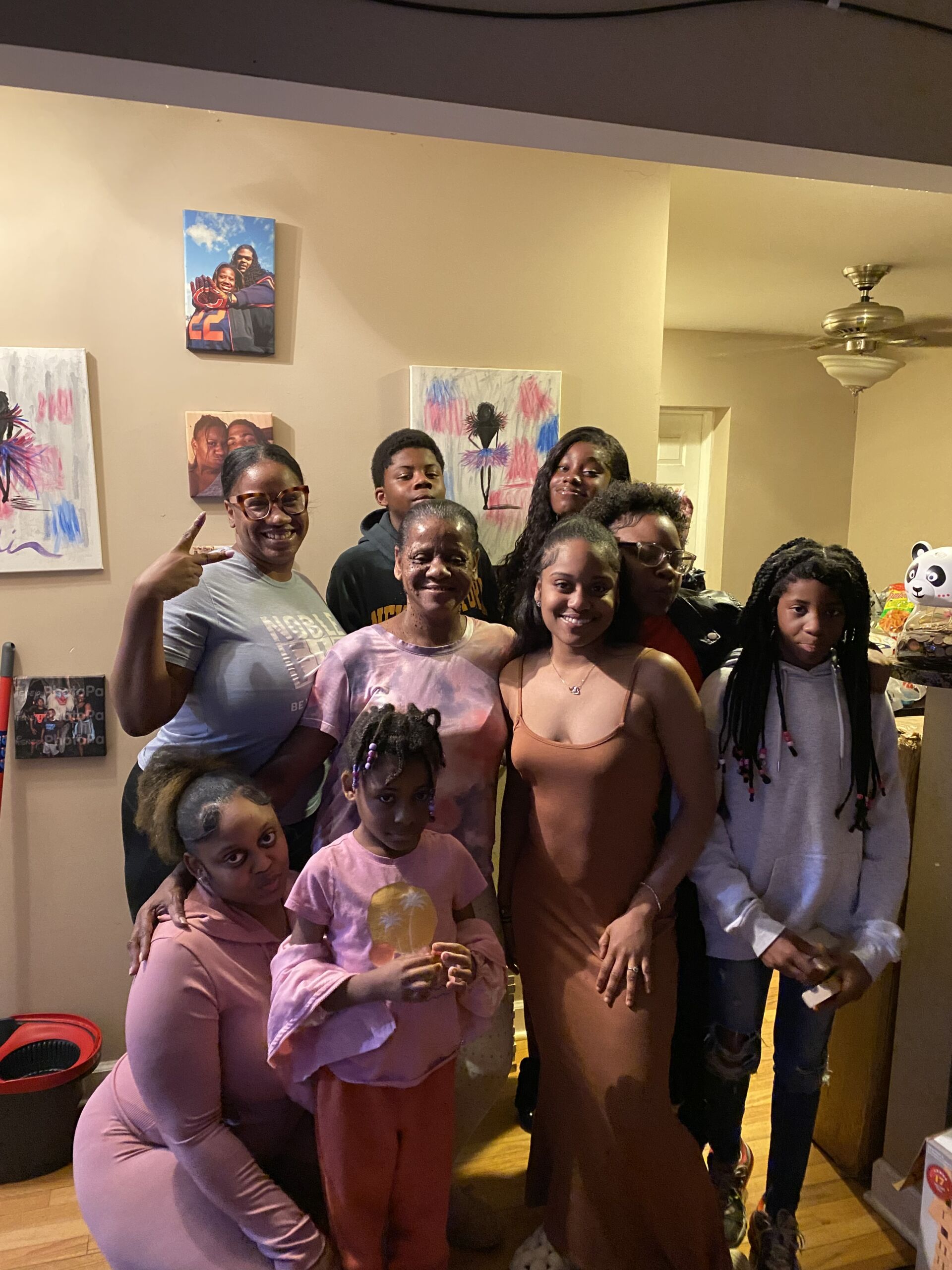 Photo shows Principal Kashawndra Wilson posing for a photo with her family at a family gathering. They are in a residental house with pieces of art and photos behind them.