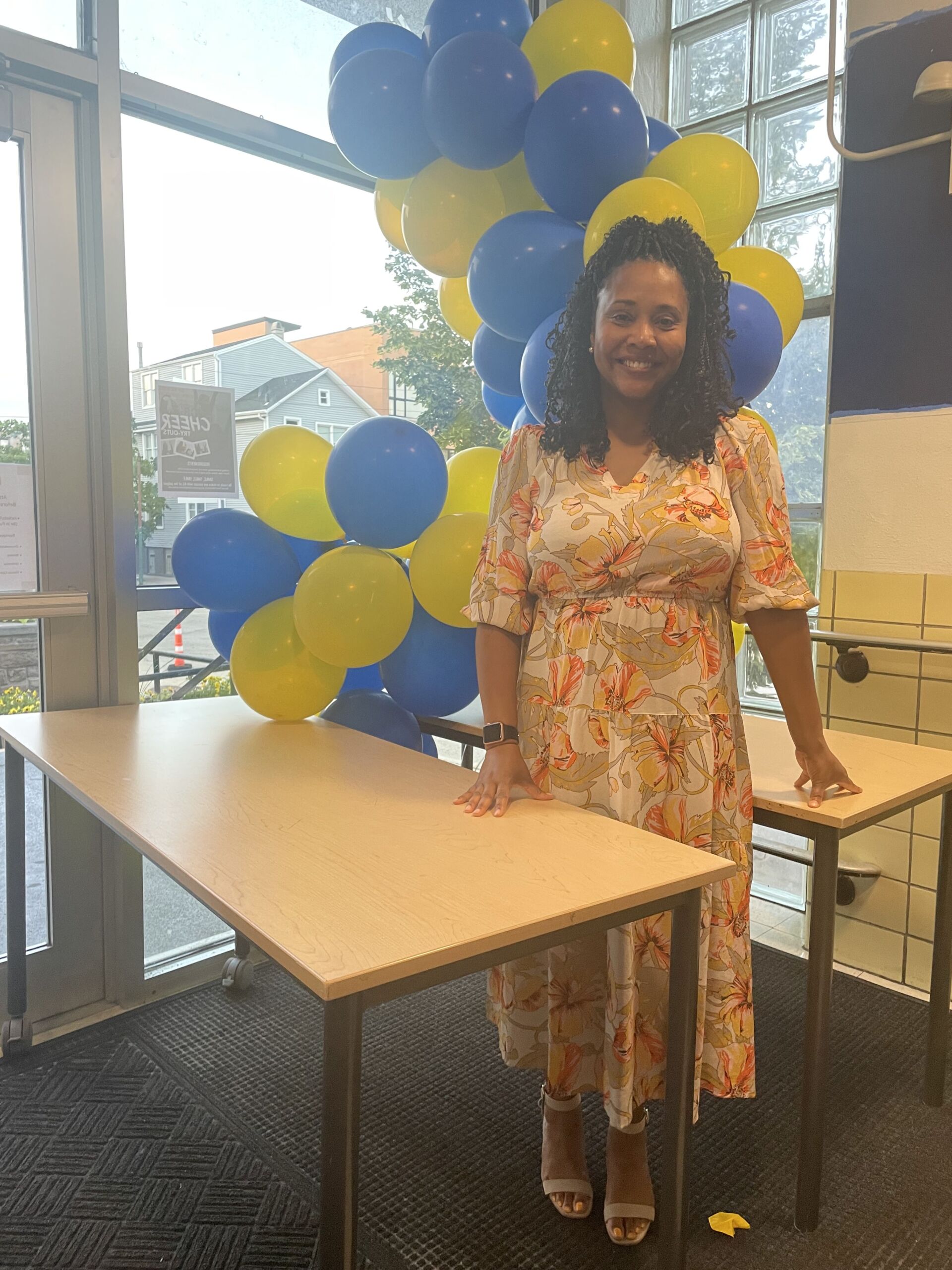 bennett standing smiling next to blue and yellow balloons
