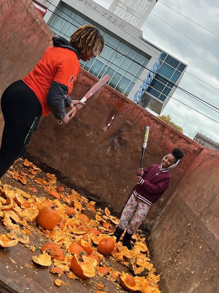 Hemingway and a young girl smashing pumpkins with a bat