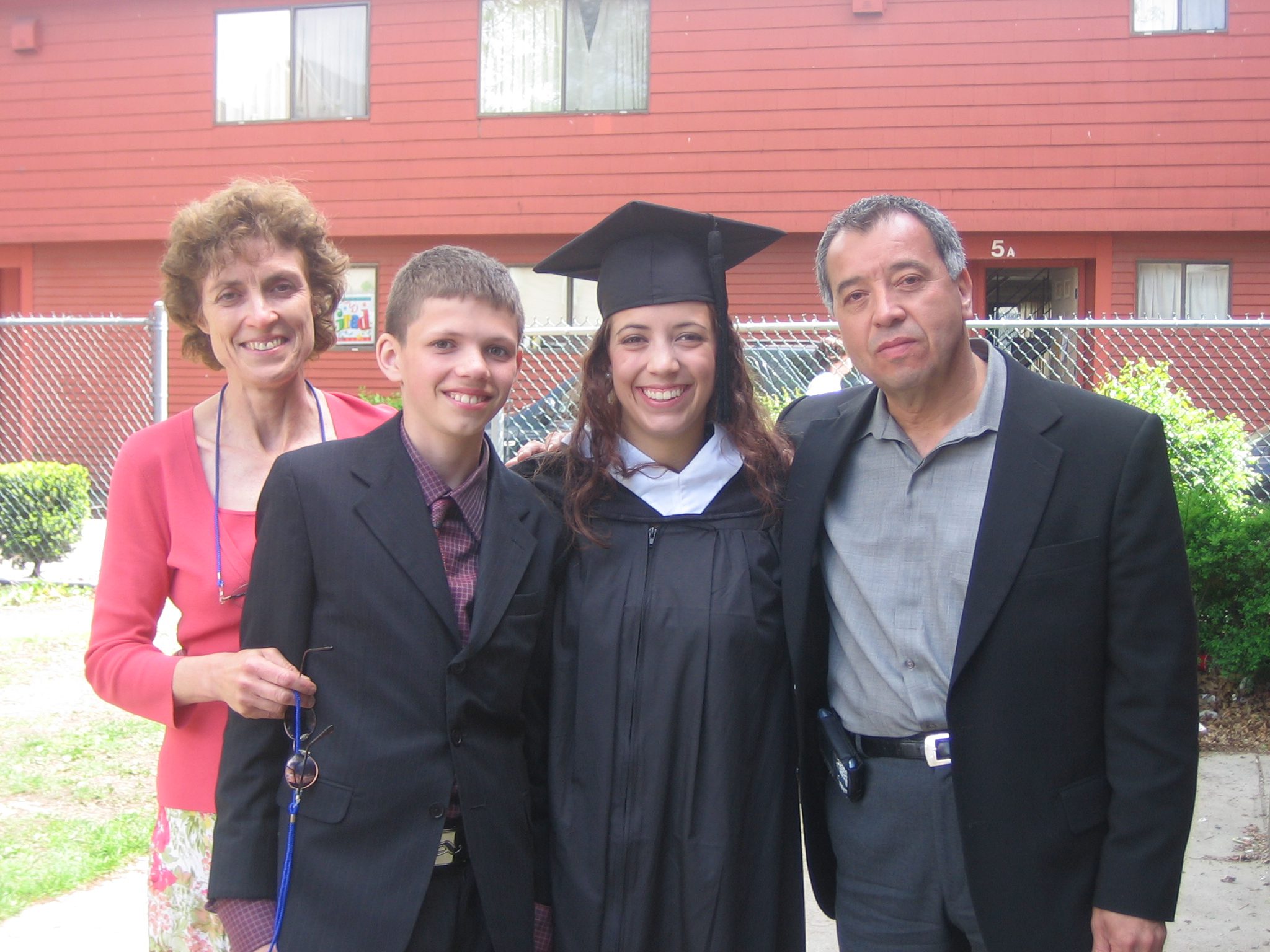 moya and family outside smiling, moya is wearing a graduation cap and gown