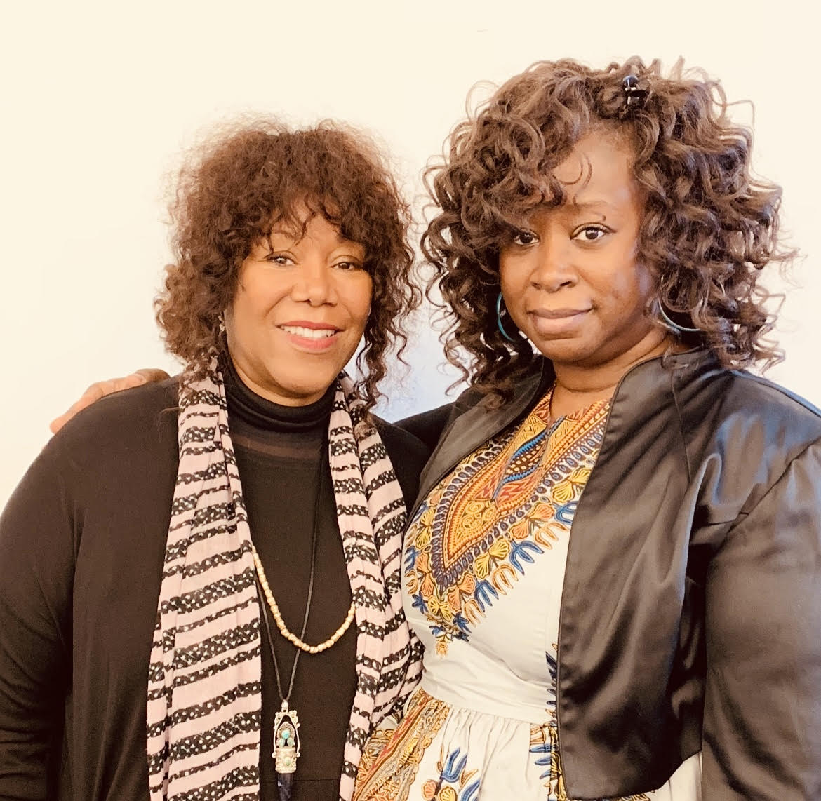 In this photo, you can see Tanisha Hall posing with Ruby Bridges. Hall has her arm over Bridges' shoulders as they both smile at the camera.