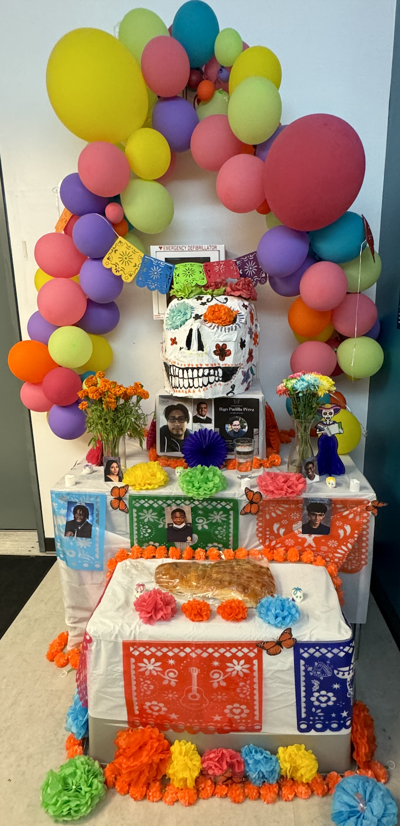 Ofrenda that is decorated with skulls, flowers, and pictures of loved ones.