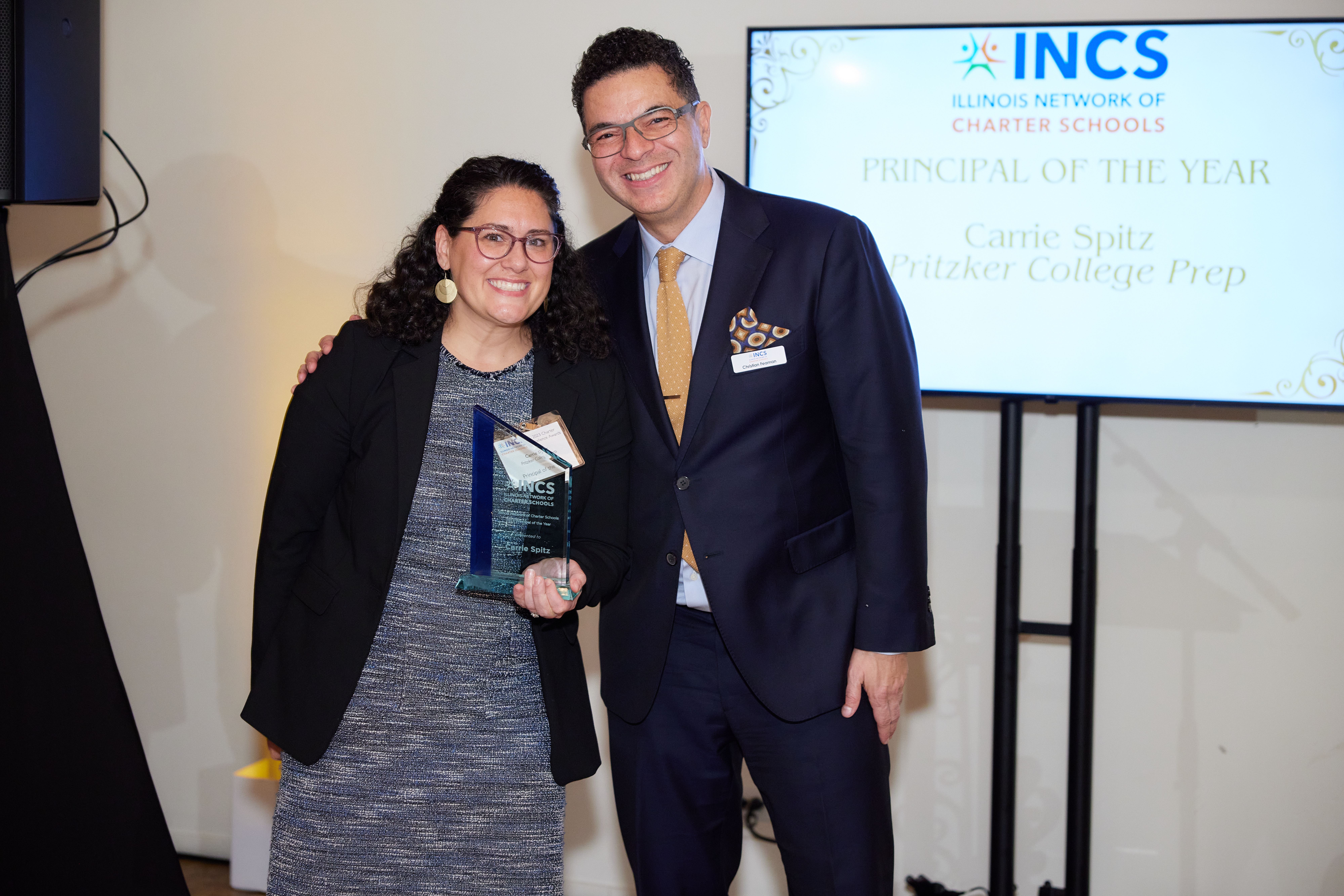 In this photo, Principal Carrie Spitz of Pritzker College Prep is receiving her award from hristian Feaman, the director of district advocacy at INCS.