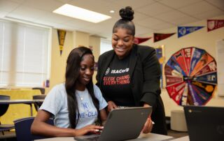 This photo shows a staff member at Rowe-Clark Math & Science Academy helping a student on her laptop.