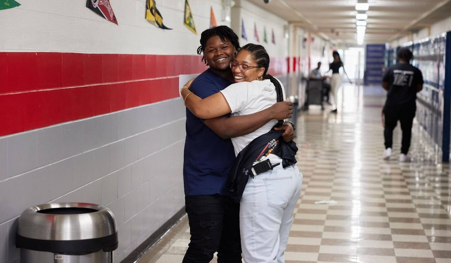 Student and assistant principal greeting each other with a hug in the hallway at Johnson College Prep