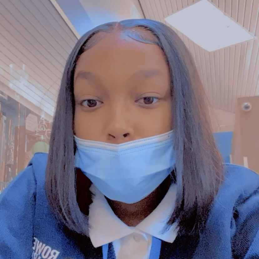 Photo shows a selfie of Shyanne S, a senior at Rowe-Clark Math & Science Academy. She is a young Black woman with short straight brown hair. She is wearing a mask, a Rowe-Clark sweater, and a white button-up shirt.