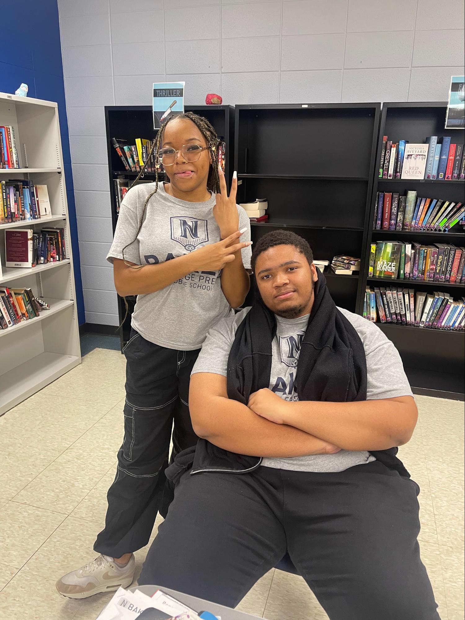 In this photo, Lion's Pride student mentor and Baker College Prep senior Antynece is standing behind her mentee, Bryan, who is sitting. They are both smiling and posing for the camera.