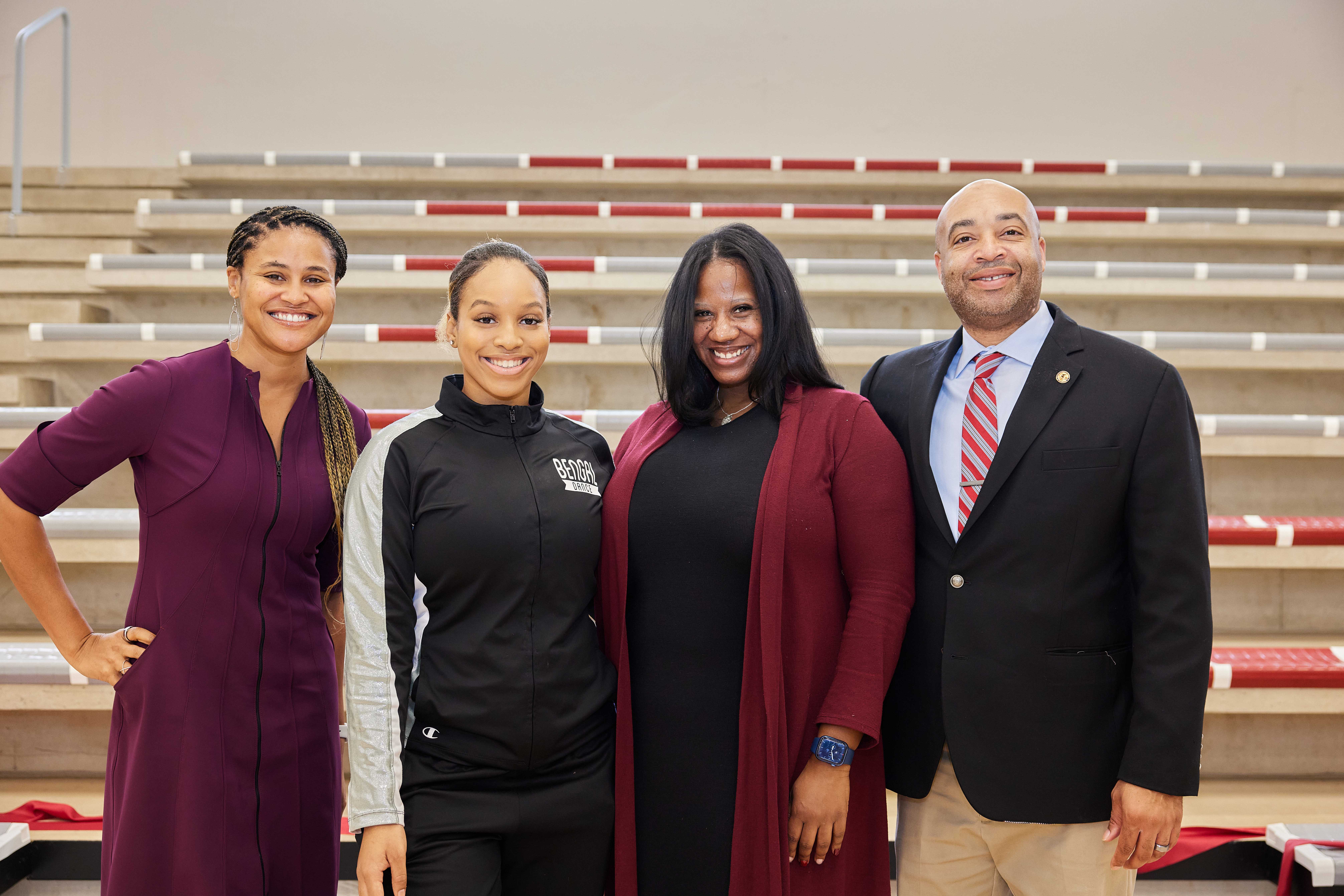 This is a group photo of all the speakers for Hansberry College Prep's gym ribbon-cutting ceremony. They are smiling and standing in front of the new bleachers.