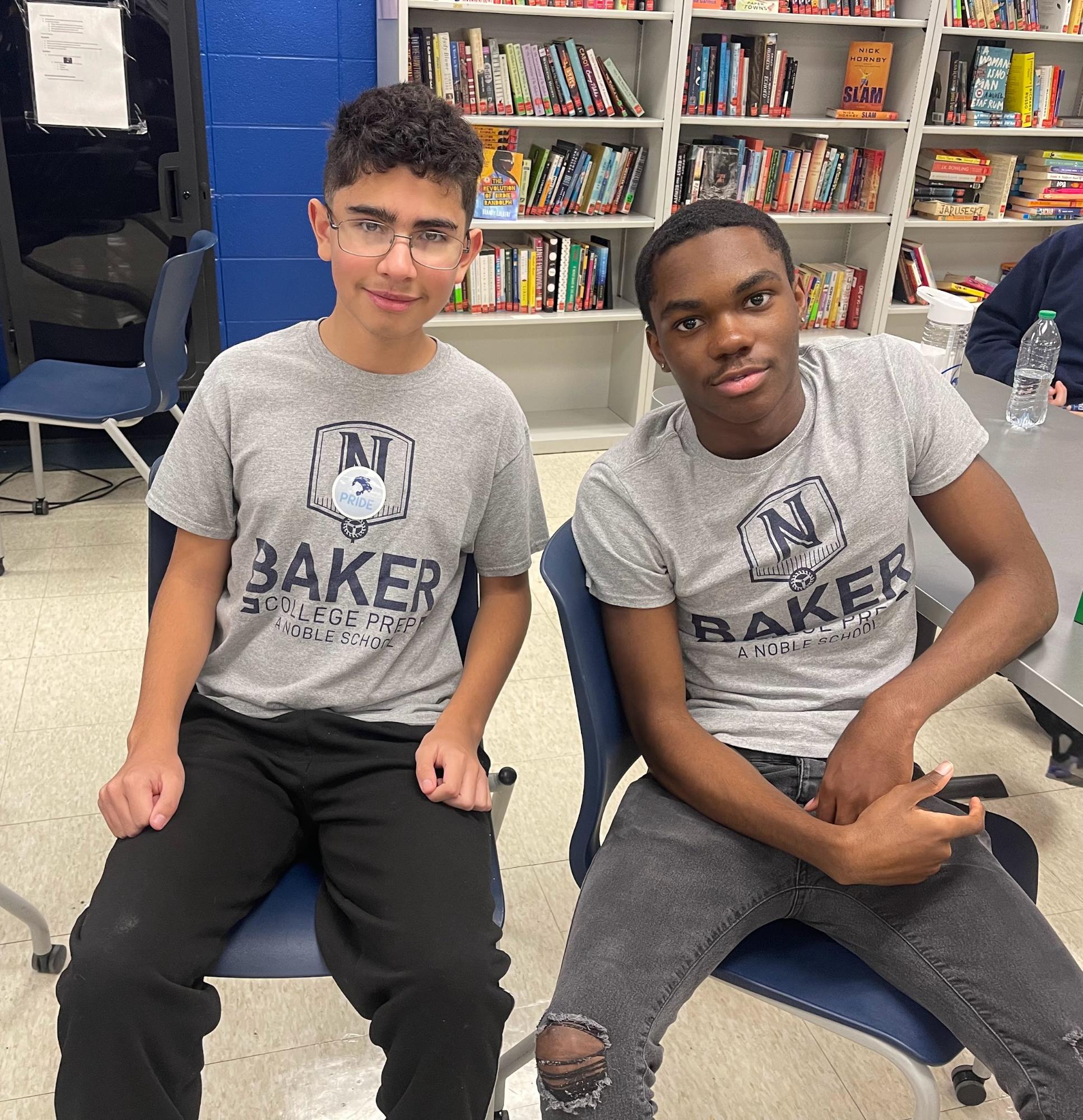In this photo, Zayden, a freshman at Baker College Prep, is sitting beside his mentor, Tavin, a senior at Baker. They are both smiling at the camera.