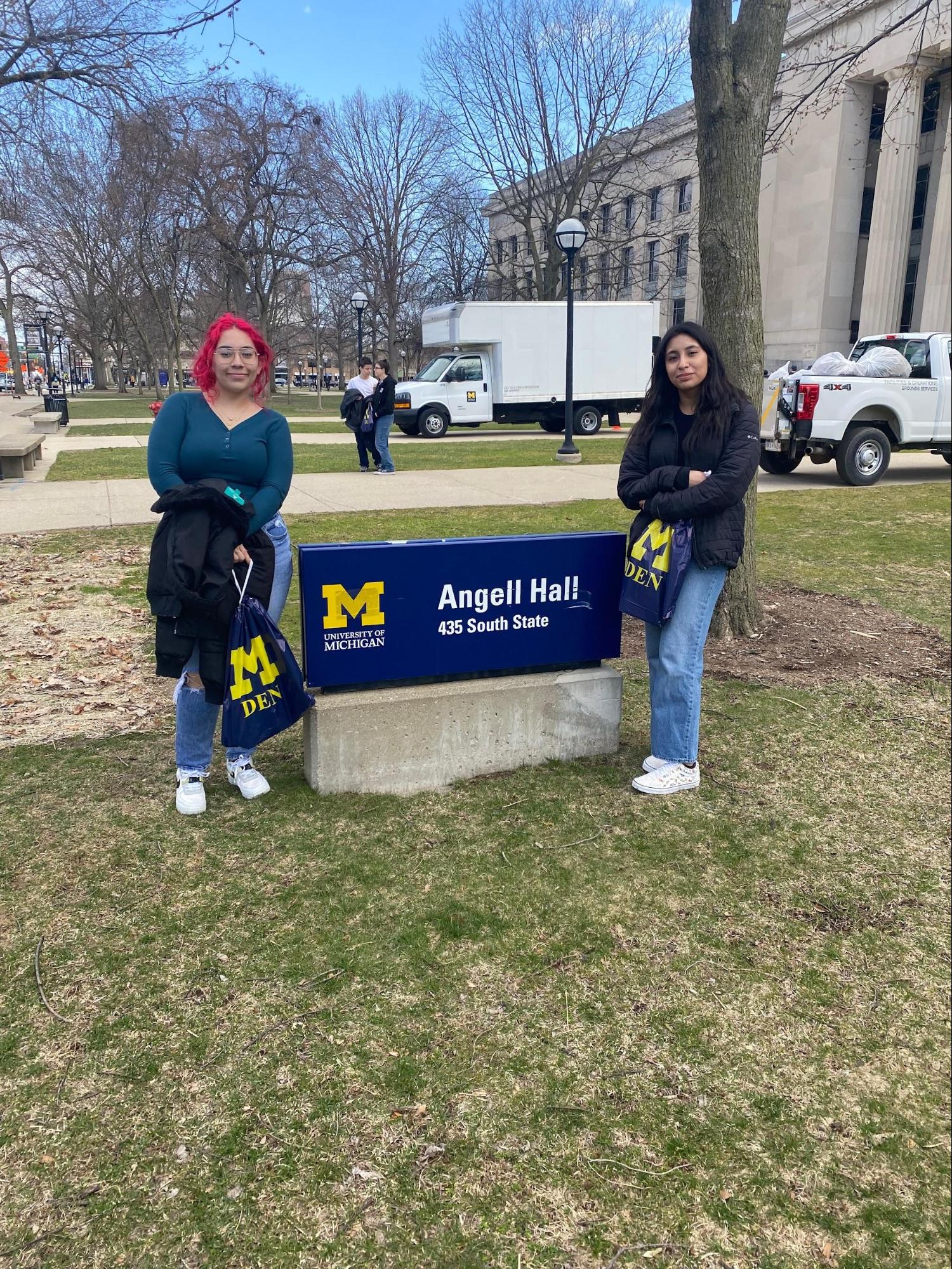 Harumi and classmate poses on University of Michigan Campus. THey are b oth standing in the grass next to the "Angel Hall" sign.