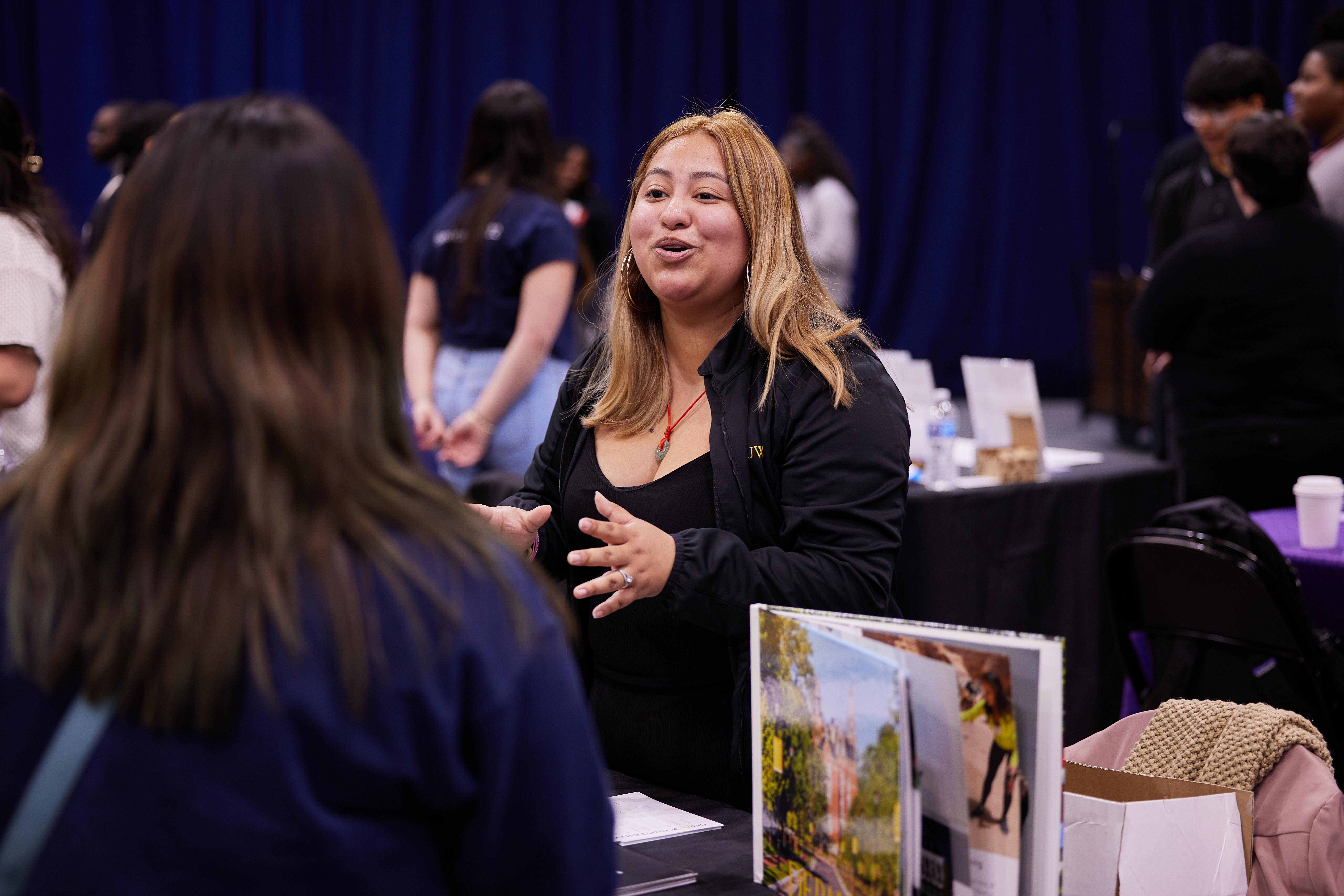 This photo shows Mari Santillan, a Pritzker College Prep alum, talking with current Noble Schools students at the annual junior college fair. She is now the assistant director of admission and diversity at DePauw University.