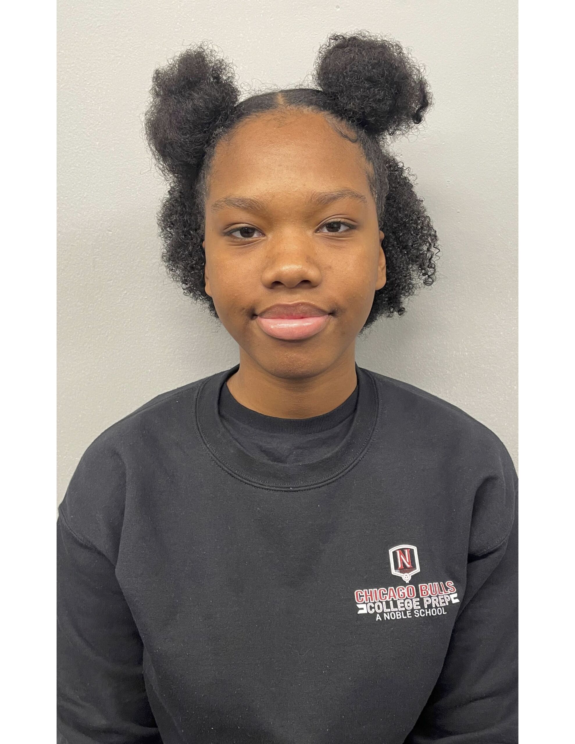 Photo shows a headshot of Madison Welch, a student at Chicago Bulls College Prep. She is a young Black woman with medium-length hair put up into two buns. She is wearing a black sweatshirt with the Bulls Prep logo on it.