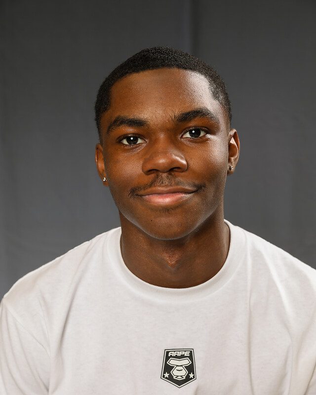 Image shows a headshot of Tavin McCree, a student at Baker College Prep. He is a young Black man with short hair. He is smiling with a white t-shirt on.