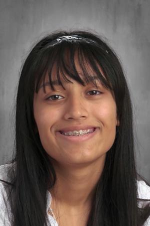 Image shows a school headshot of Jocelyn Pacheco, a rising junior at Muchin College Prep. She is a young Latine girl with medium-length, straight, black hair. She is smiling and wearing a white button-up.