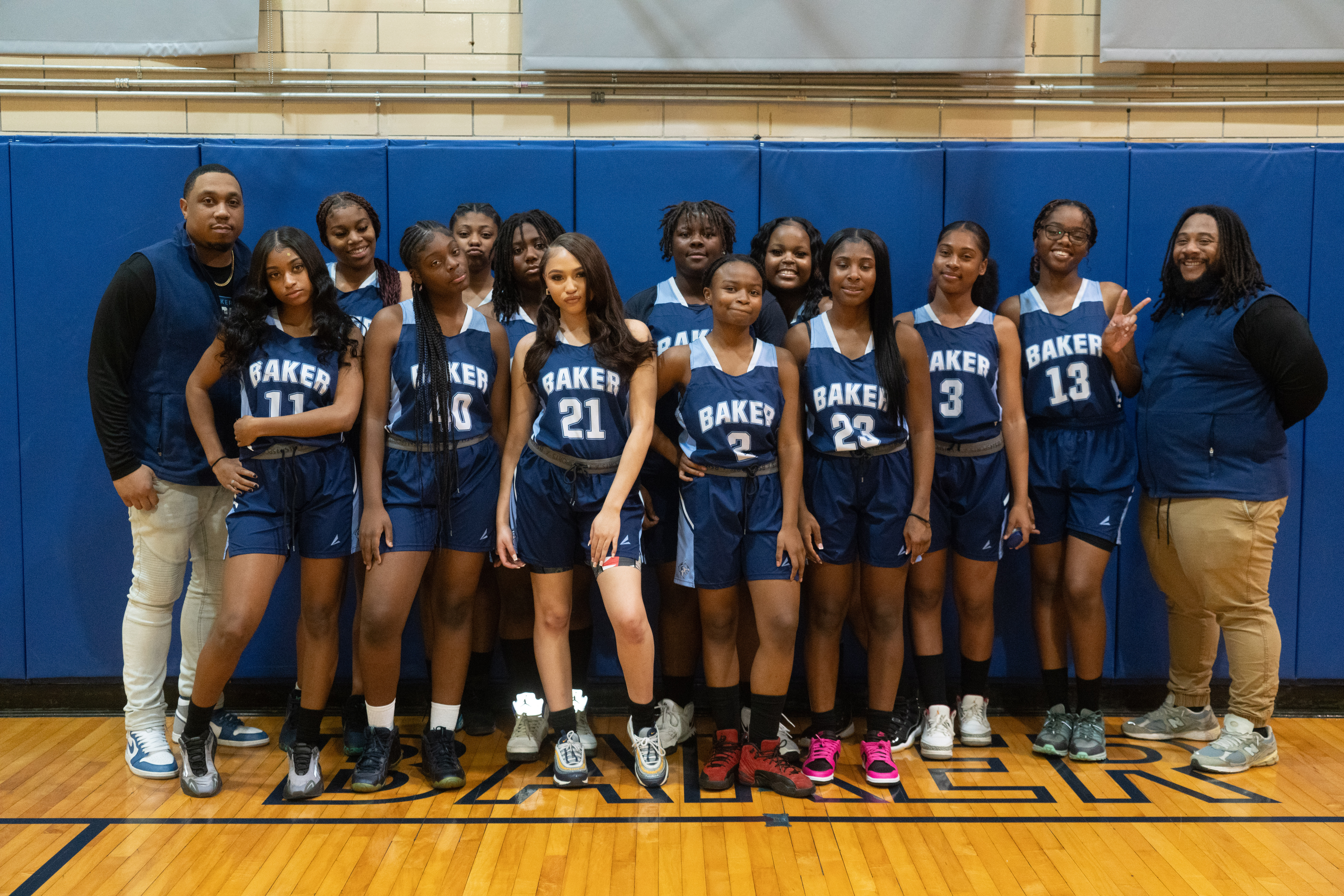 Image shows a group shot of Baker College Prep's girls varsity basketball team for the 2023-2024 school year. They are all in uniform and standing in a gym.