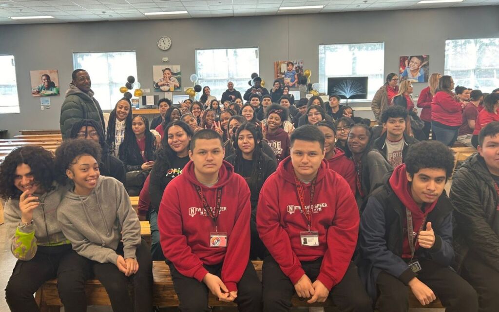 Photo shows a group shot of Black and Brown students at ITW David Speer Academy assembled for a Black & Brown Solidarity Club meeting. They are all smiling and posing for the camera.
