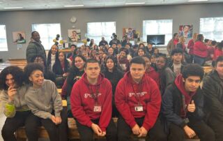 Photo shows a group shot of Black and Brown students at ITW David Speer Academy assembled for a Black & Brown Solidarity Club meeting. They are all smiling and posing for the camera.