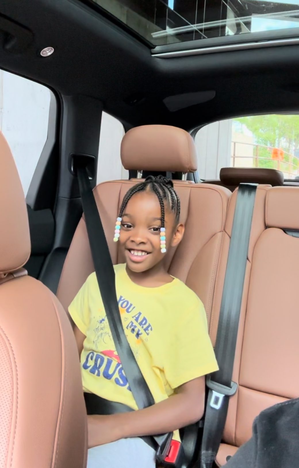 Cleaves' young daughter in the car. She is smiling brightly.