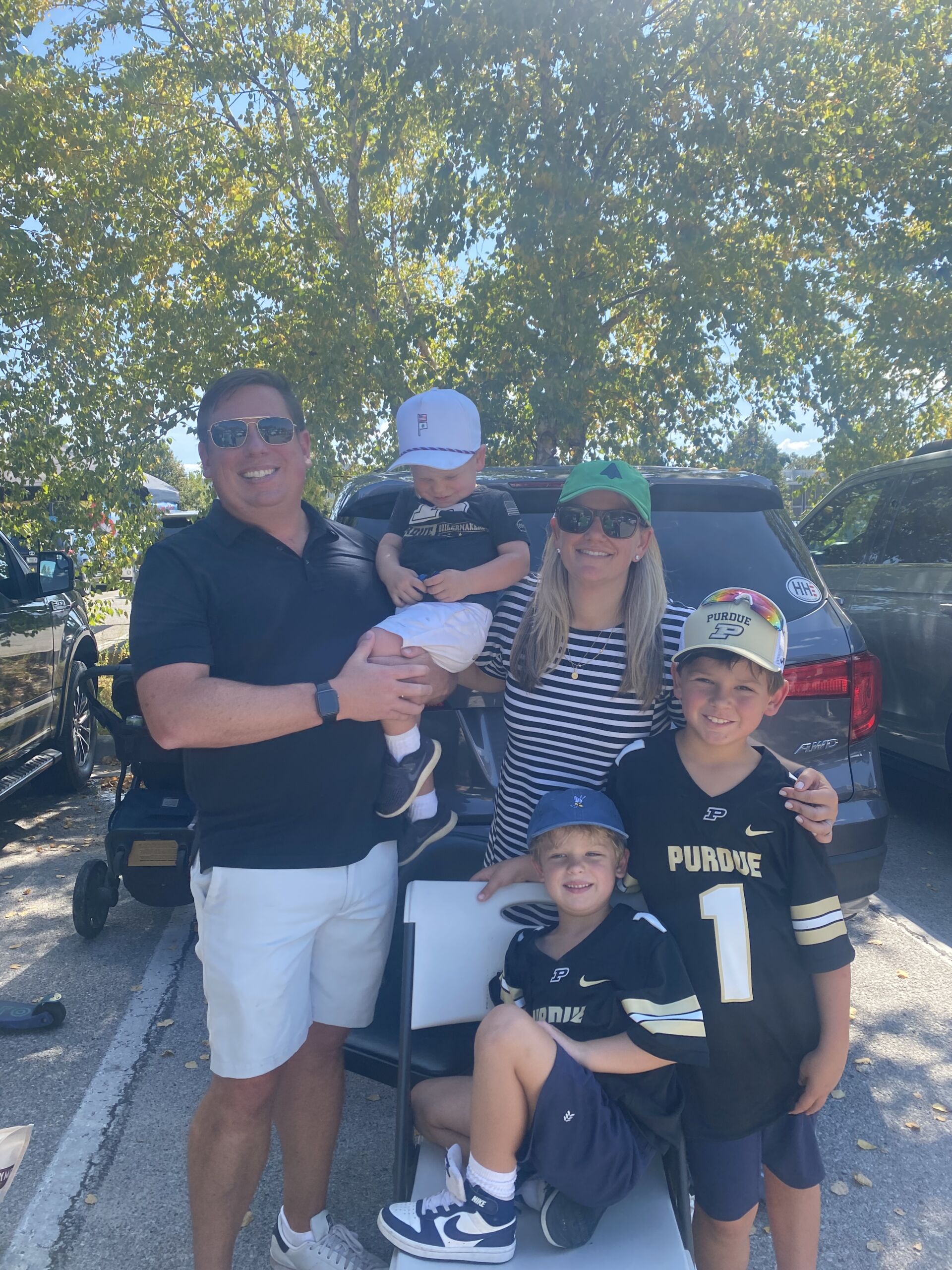 Ryden with her husband and three kids outside on a sunny day. The kids are all wearing Purdue University jerseys.