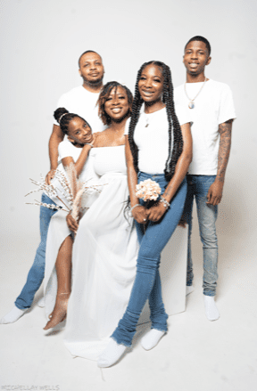 A family photo of Hemingway and her family. They are all dressed up in white and are posed in front of a white background.