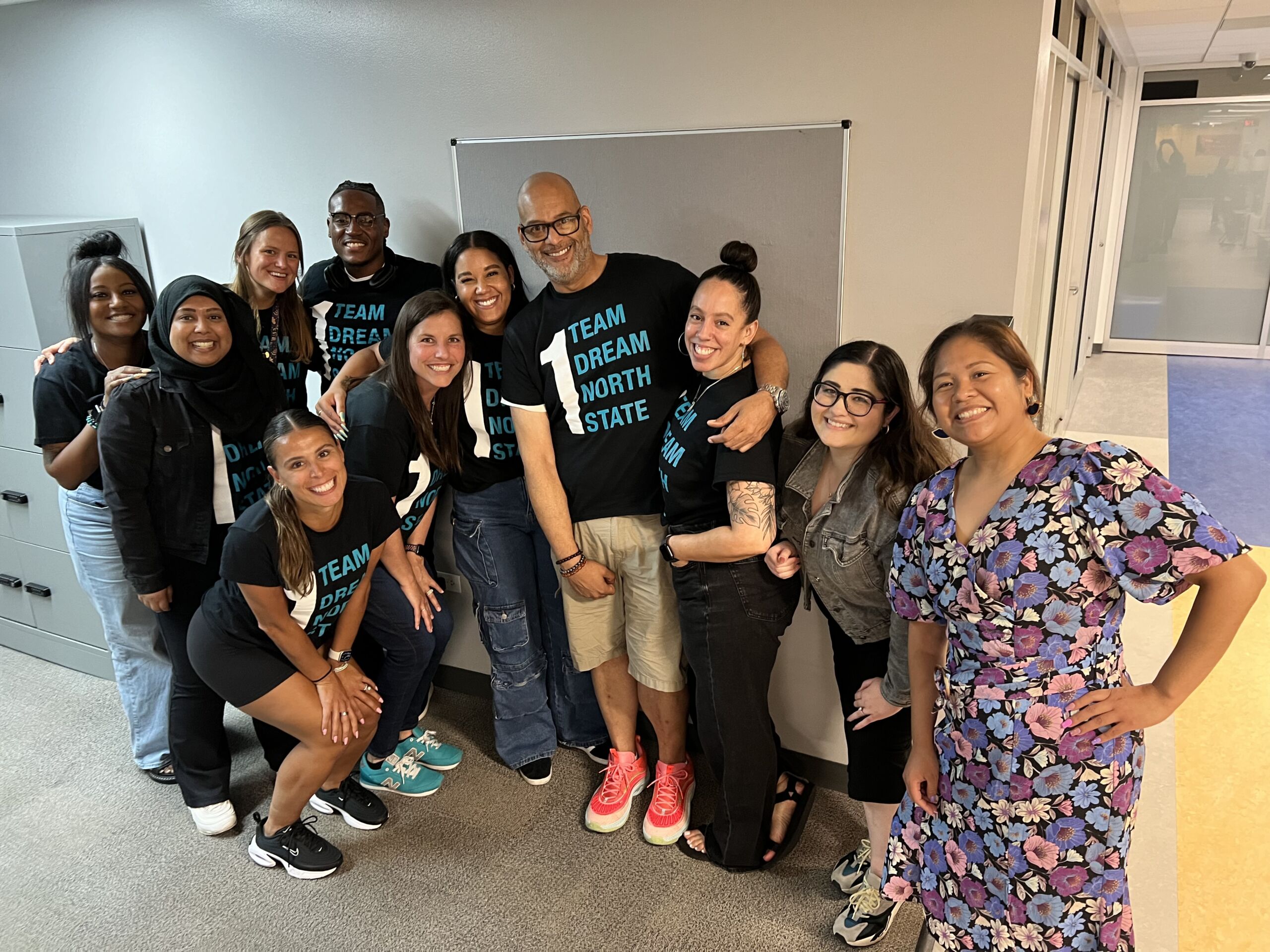 Lockhart with her staff members at Muchin College Prep. Many of them are wearing black t-shirts that say "1 Team, 1 Dream, 1 North State"