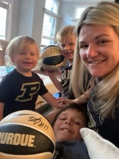 Selfie of Ryden with her three young kids. They are all wearing Purdue University shirts and holding signed Purdue basketballs.