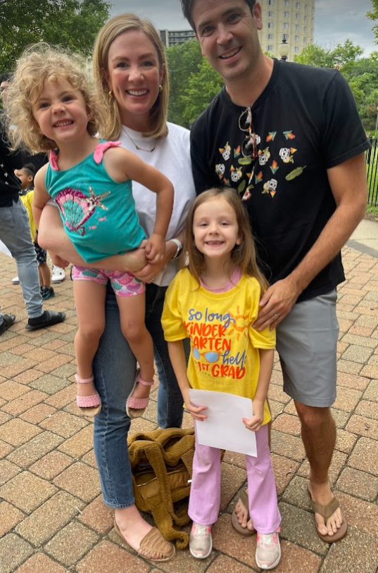 Lawrence with her husband and two small children outside on a nice day.