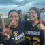 Lizbet Sanchez, a special education teacher at Mansueto High School, poses with two of her students in front of a football field.