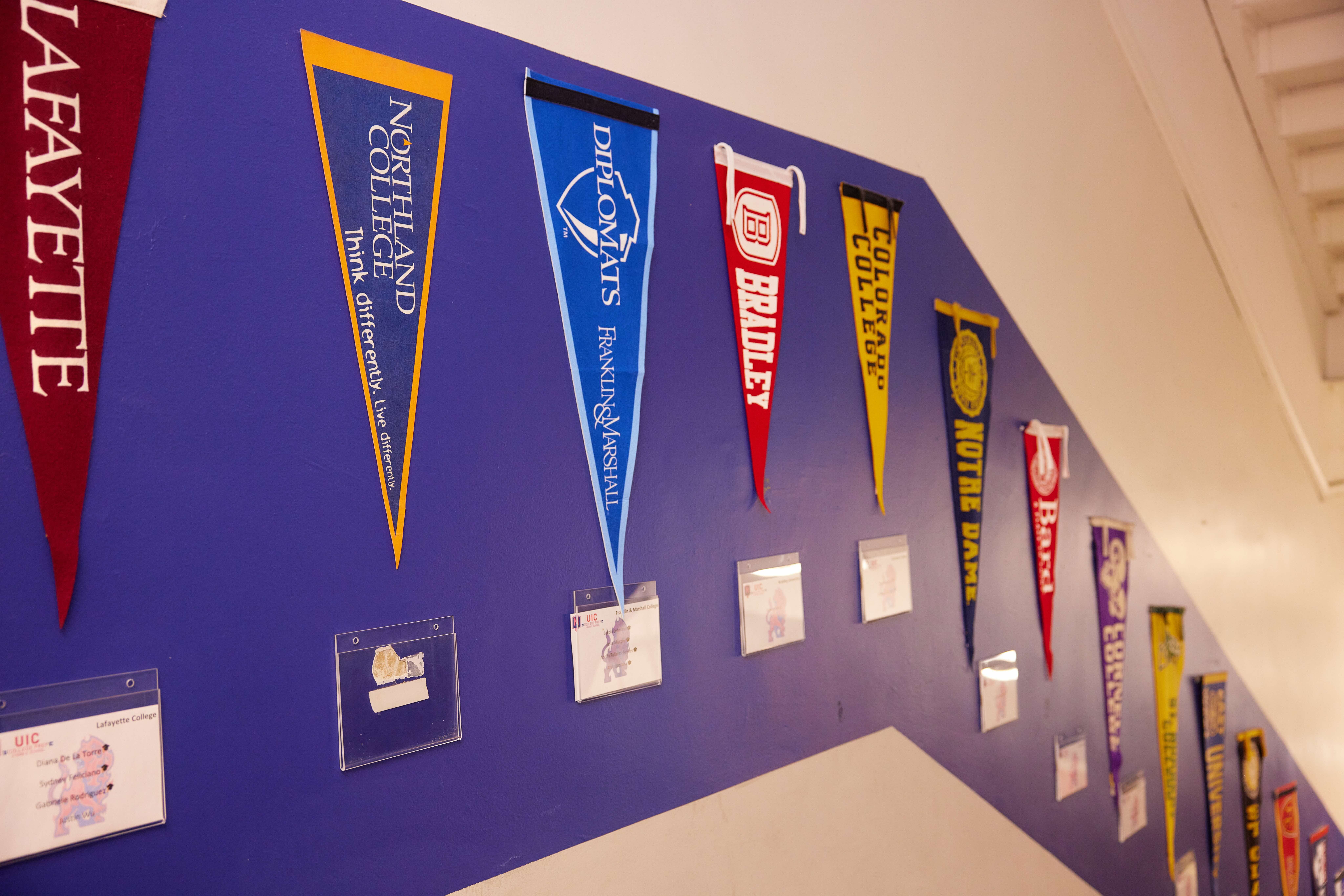 uiccp college penants Many college pennants line a bold blue line on a wall in UIC College Prep hallways. Underneath them, you can see little cards that have names of students on them.