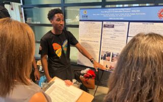 Jamill Willis, a student at DRW College Prep, points to a posterboard with his group's Together Towards Peace project, which addresses gun violence in our communities.