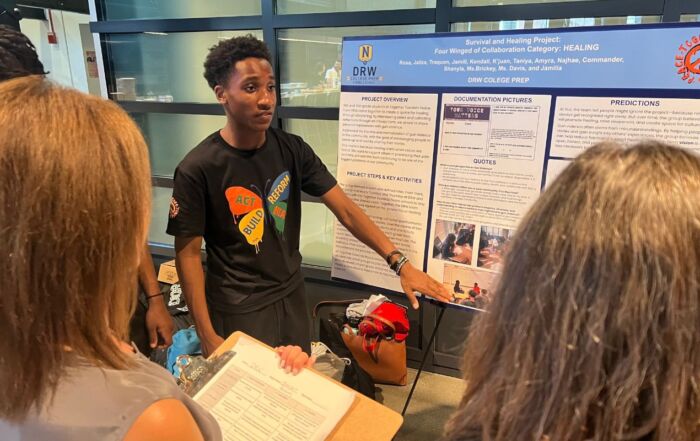 Jamill Willis, a student at DRW College Prep, points to a posterboard with his group's Together Towards Peace project, which addresses gun violence in our communities.