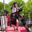 Luis Ramos points confidently at the camera, college diploma in hand and decked out in his graduation robes, as he walks off the stage. He is a young man with short dark brown hair, a light beard, and brown skin.