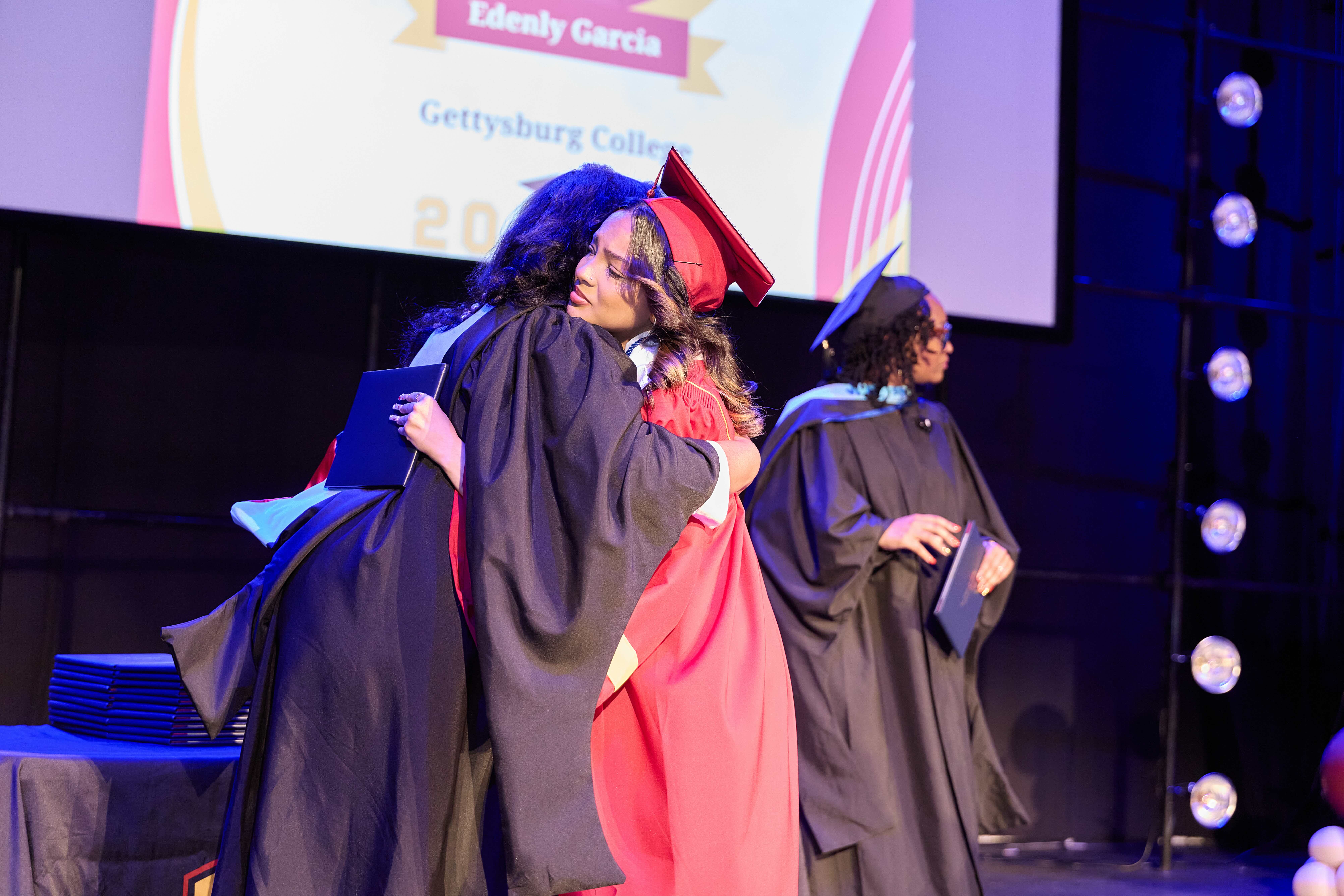 A TNA senior gives her advisor a hug as she crosses the stage to receive her diploma.