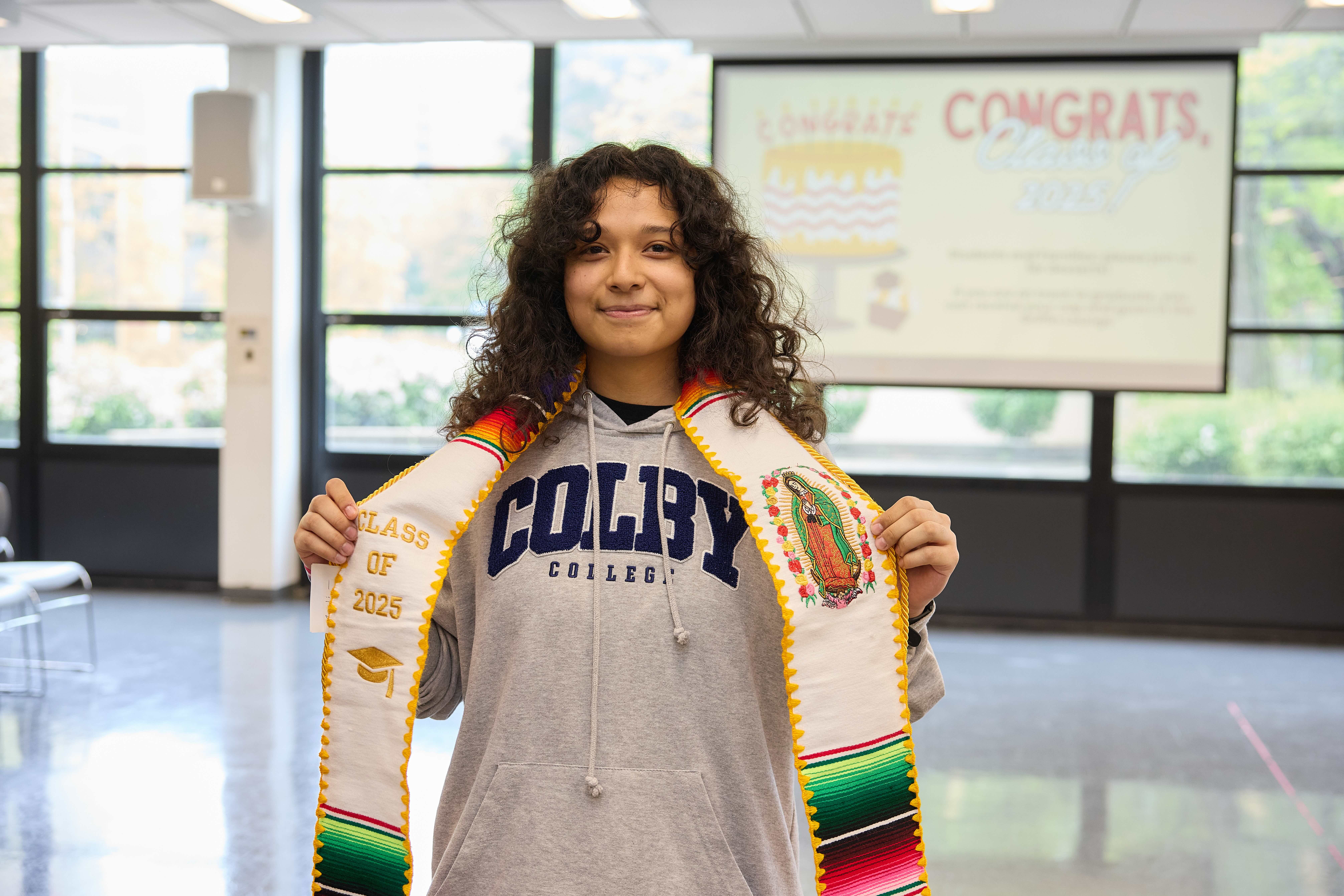 A TNA senior poses for a photo with her Hispanic graduation sash and her Colby College sweatshirt